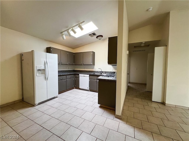 kitchen featuring rail lighting, lofted ceiling, sink, light tile patterned floors, and white appliances