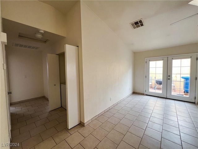 tiled empty room featuring lofted ceiling and french doors