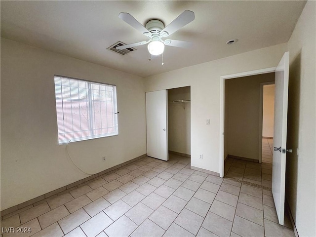 unfurnished bedroom with ceiling fan, a closet, and light tile patterned floors