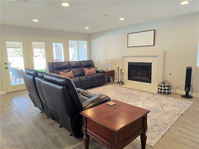 living room featuring a tile fireplace, a wealth of natural light, and hardwood / wood-style floors