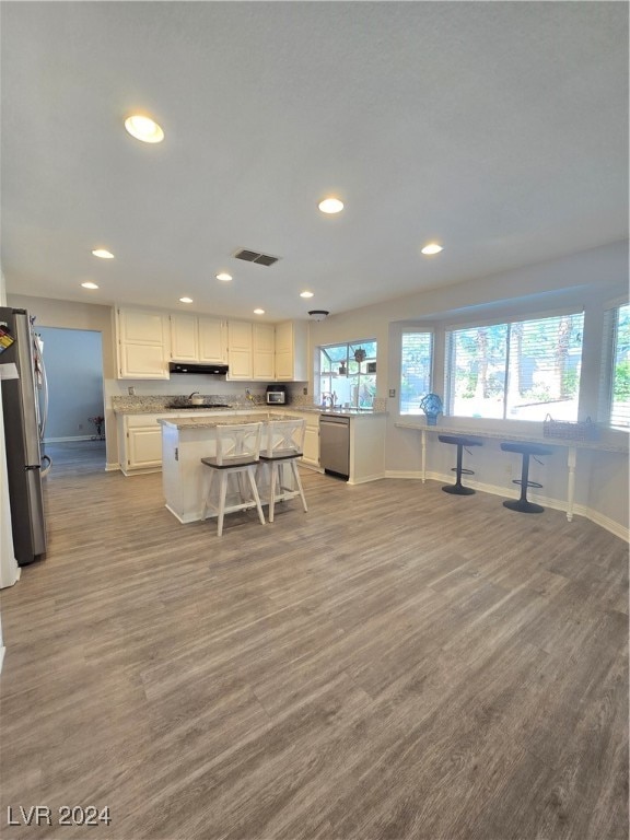 kitchen featuring white cabinetry, light hardwood / wood-style floors, a breakfast bar, a kitchen island, and appliances with stainless steel finishes