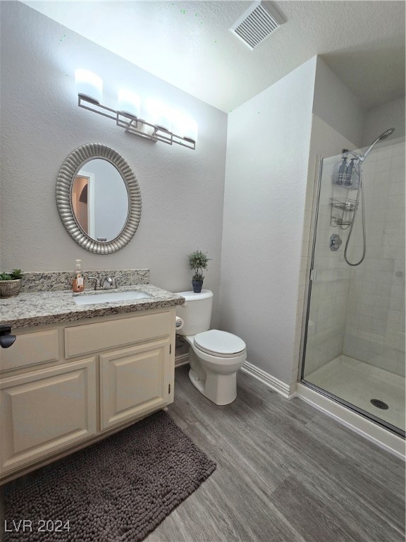 bathroom with vanity, hardwood / wood-style flooring, toilet, and an enclosed shower