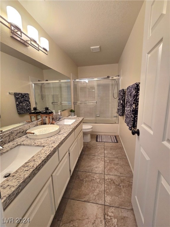 full bathroom with a textured ceiling, vanity, toilet, and bath / shower combo with glass door