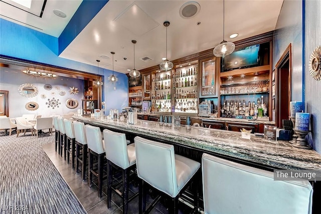 bar featuring stone counters, dark tile patterned flooring, and decorative light fixtures