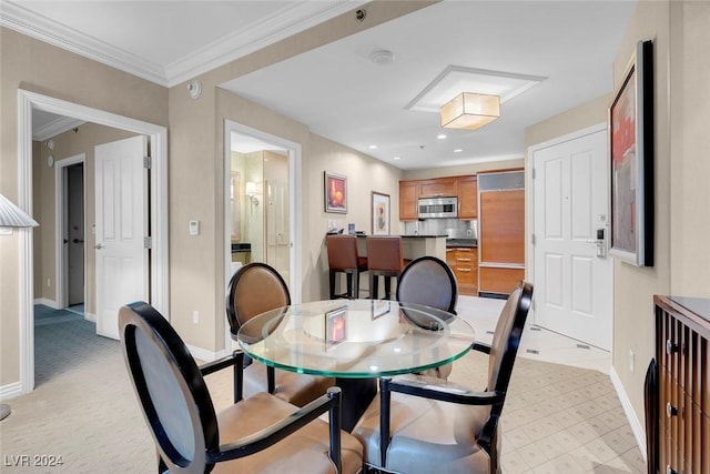 dining area with crown molding and light colored carpet