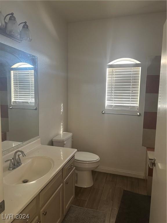 bathroom with toilet, vanity, and hardwood / wood-style flooring