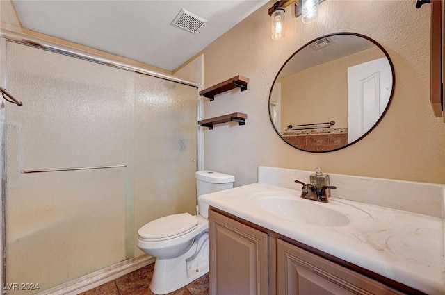 bathroom featuring toilet, vanity, a shower stall, and visible vents