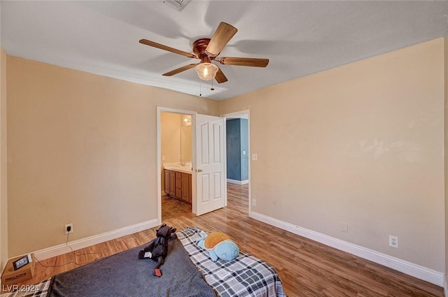 exercise area featuring light wood-style floors, ceiling fan, and baseboards