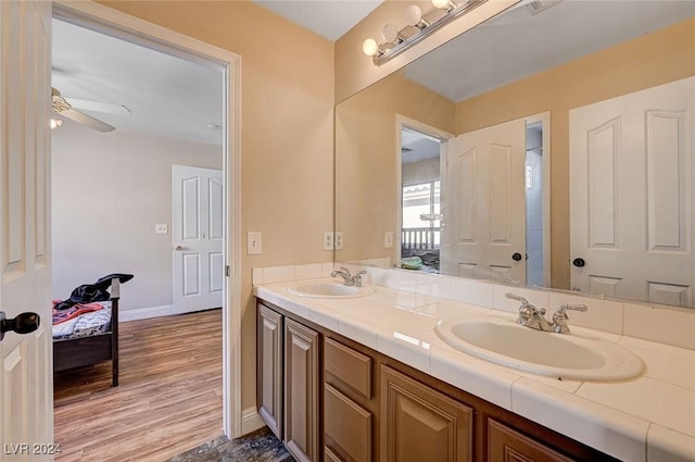 full bath featuring a ceiling fan, wood finished floors, a sink, and double vanity