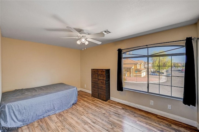 bedroom featuring baseboards, visible vents, ceiling fan, and wood finished floors