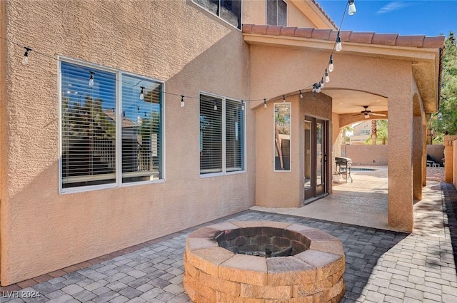 view of patio / terrace with an outdoor fire pit, fence, and a ceiling fan