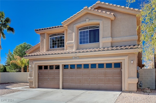 view of front of house with driveway, an attached garage, fence, and stucco siding