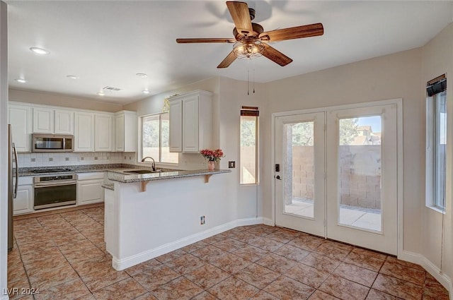 kitchen featuring a breakfast bar area, tasteful backsplash, appliances with stainless steel finishes, white cabinets, and a peninsula