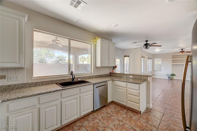 kitchen featuring light tile patterned floors, a peninsula, a sink, visible vents, and stainless steel dishwasher