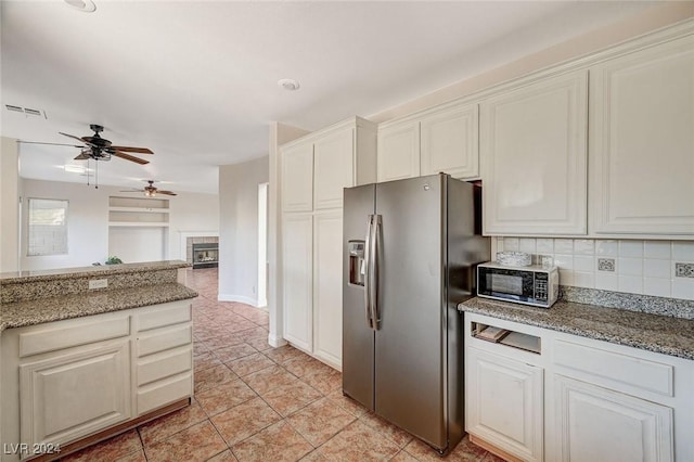 kitchen featuring a fireplace, visible vents, decorative backsplash, white cabinets, and stainless steel fridge with ice dispenser