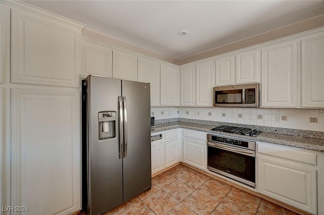 kitchen with stainless steel appliances, white cabinetry, decorative backsplash, and light stone countertops