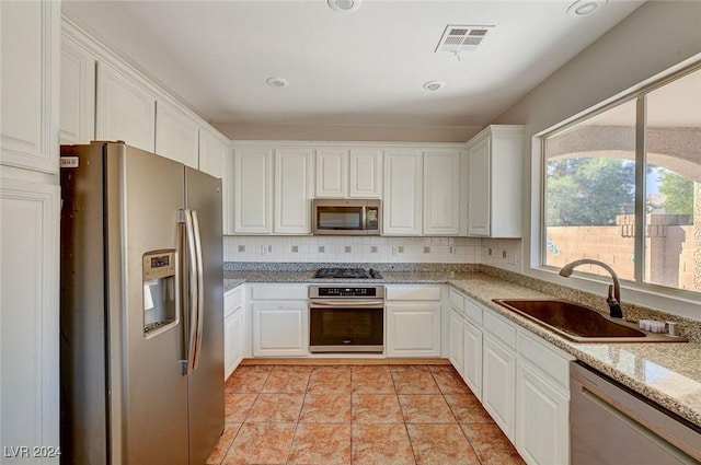 kitchen featuring visible vents, backsplash, appliances with stainless steel finishes, white cabinetry, and a sink