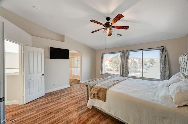 bedroom featuring arched walkways, wood finished floors, visible vents, baseboards, and vaulted ceiling