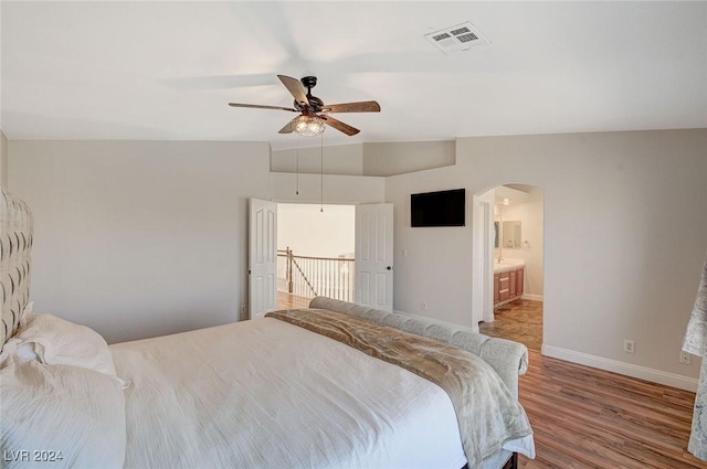 bedroom featuring arched walkways, wood finished floors, a ceiling fan, visible vents, and baseboards