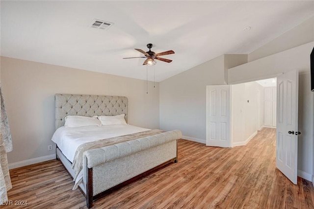 bedroom with lofted ceiling, light wood finished floors, baseboards, and visible vents