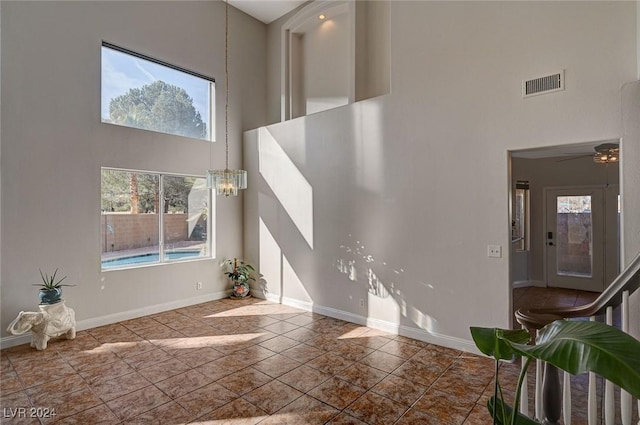 living area featuring a towering ceiling, baseboards, and visible vents