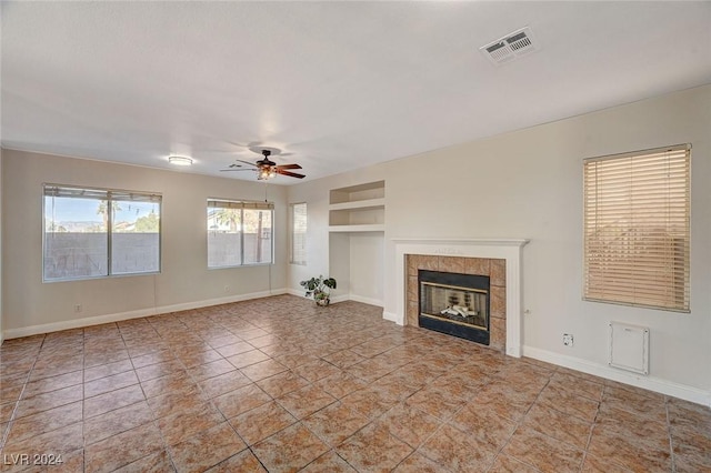 unfurnished living room featuring baseboards, visible vents, ceiling fan, built in shelves, and a fireplace