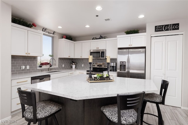 kitchen featuring light wood-type flooring, a breakfast bar, stainless steel appliances, sink, and a kitchen island