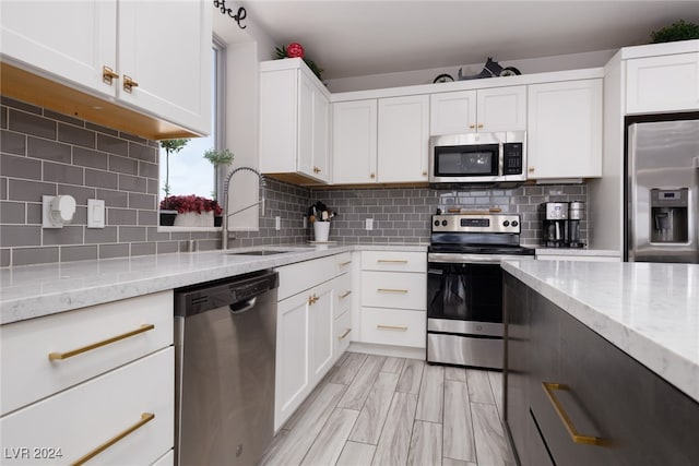 kitchen featuring white cabinets, sink, light stone countertops, tasteful backsplash, and stainless steel appliances