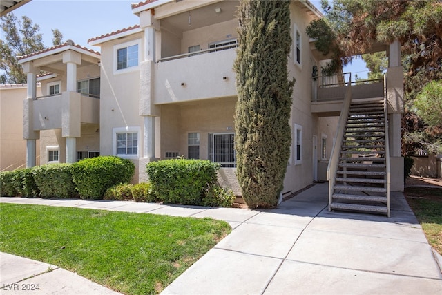 view of front facade featuring a balcony and a front yard