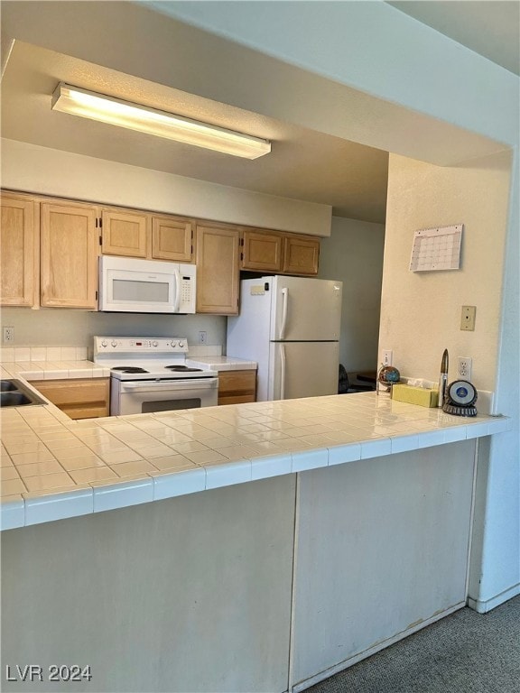 kitchen with kitchen peninsula, white appliances, carpet floors, and tile counters