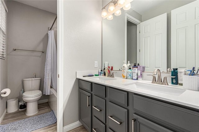 full bathroom with hardwood / wood-style flooring, vanity, shower / bathtub combination with curtain, and toilet