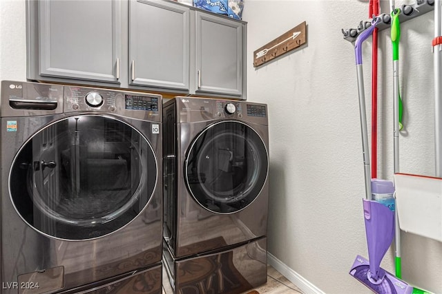 clothes washing area with separate washer and dryer and cabinets