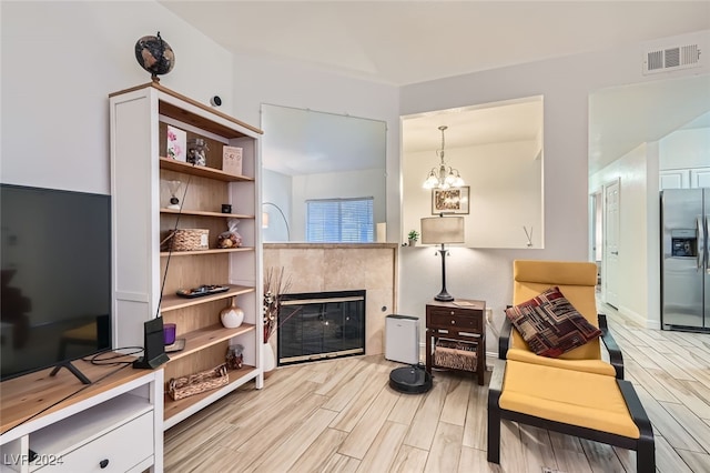 interior space with a chandelier, light hardwood / wood-style floors, and a tile fireplace