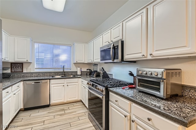 kitchen featuring white cabinets, light wood-type flooring, stainless steel appliances, and sink