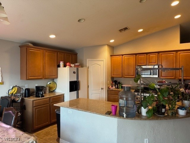 kitchen featuring lofted ceiling, light tile patterned flooring, light stone counters, and white refrigerator with ice dispenser