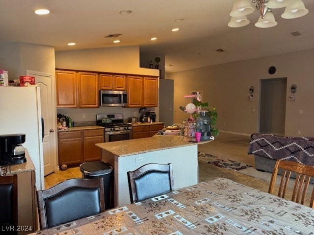 kitchen with a center island, light stone counters, pendant lighting, lofted ceiling, and appliances with stainless steel finishes