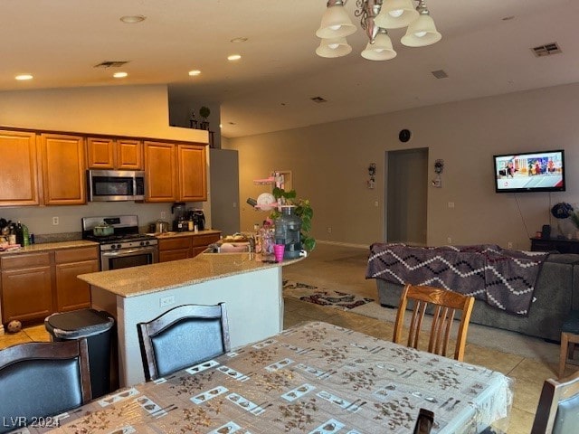 kitchen with pendant lighting, a center island, vaulted ceiling, appliances with stainless steel finishes, and light stone counters