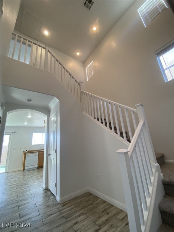 staircase with wood-type flooring and a high ceiling