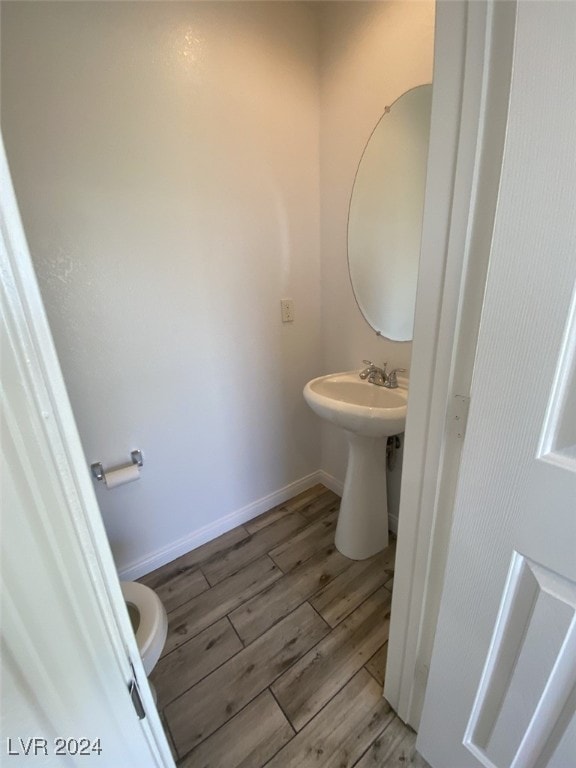 bathroom with hardwood / wood-style flooring, toilet, and sink