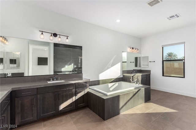 bathroom featuring tile patterned flooring, vanity, and a relaxing tiled tub