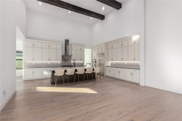 kitchen featuring beamed ceiling, a kitchen breakfast bar, light wood-type flooring, and a kitchen island with sink