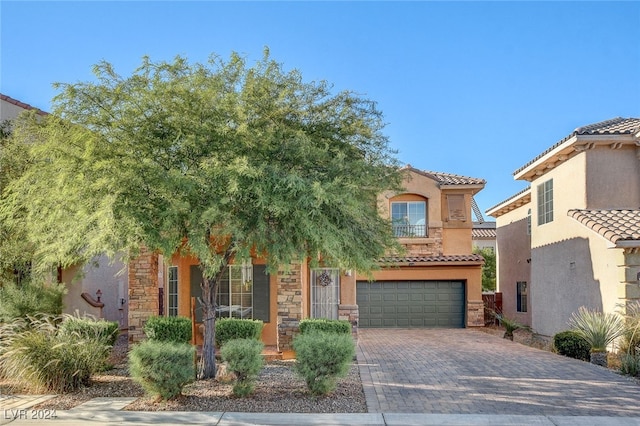 view of front of house featuring stucco siding, decorative driveway, stone siding, an attached garage, and a tiled roof