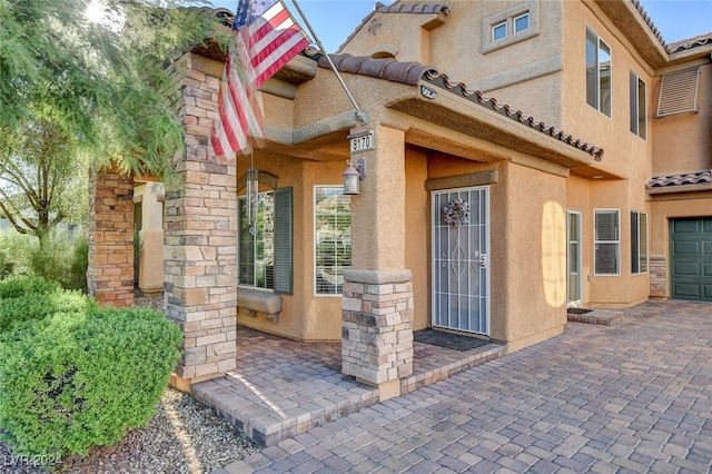 entrance to property featuring stucco siding, a garage, and a tile roof