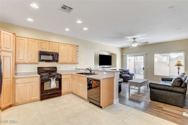 kitchen featuring visible vents, light brown cabinetry, open floor plan, black appliances, and a sink