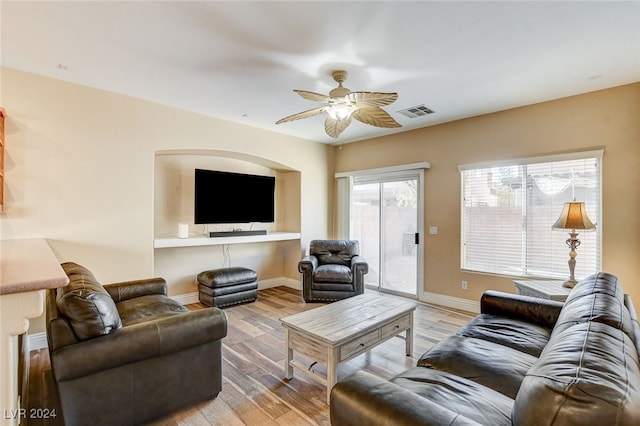 living room with baseboards, a ceiling fan, visible vents, and light wood-type flooring