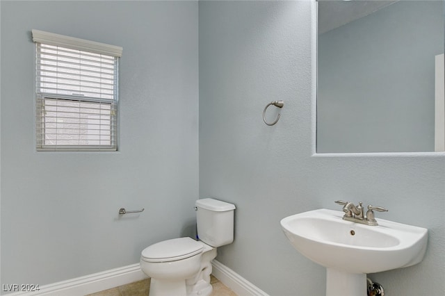 bathroom with a sink, baseboards, toilet, and tile patterned floors