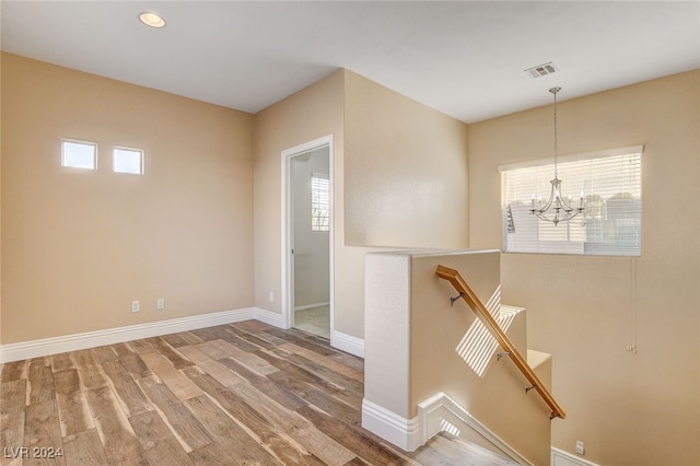 empty room featuring visible vents, baseboards, recessed lighting, wood finished floors, and a notable chandelier