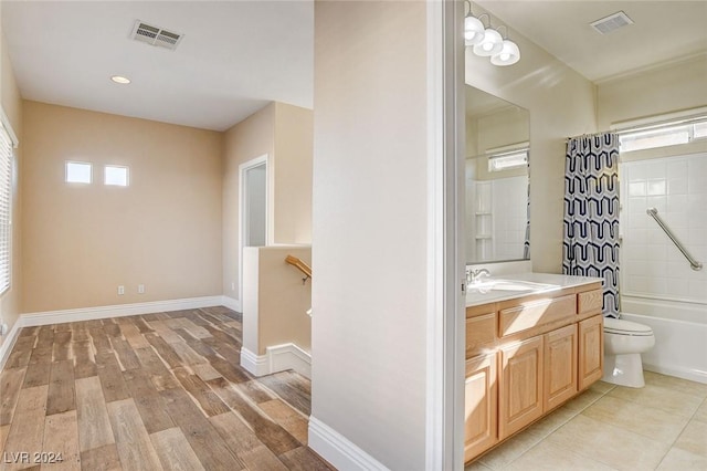 full bath with vanity, shower / bathtub combination with curtain, wood finished floors, visible vents, and baseboards