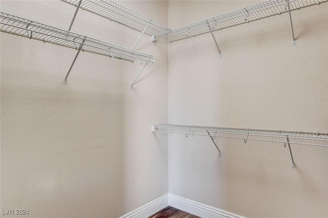 walk in closet with dark wood-style flooring