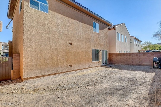 rear view of house featuring fence and stucco siding